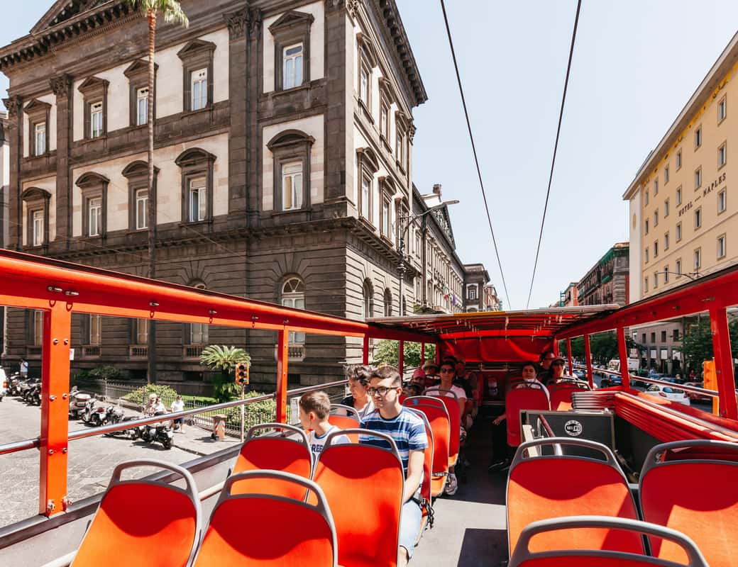 Rode hop-on hop-off sightseeingbus in Napels met toeristen op het open dak