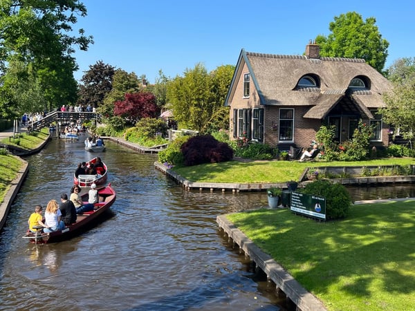 Traditional thatched-roof farmhouse on a peaceful canal in Giethoorn, the fairytale village of the Netherlands Traditional thatched-roof farmhouse on a peaceful canal in Giethoorn, the fairytale village of the Netherlands