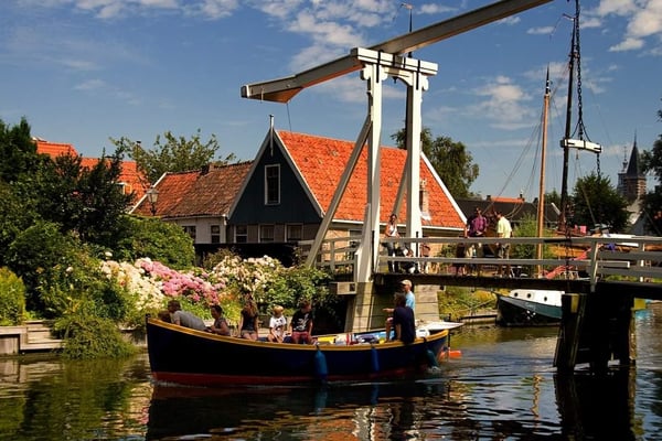 Private luxury car tour on a Dutch countryside road with historic windmills of Zaanse Schans in the background. Private luxury car tour on a Dutch countryside road with historic windmills of Zaanse Schans in the background.