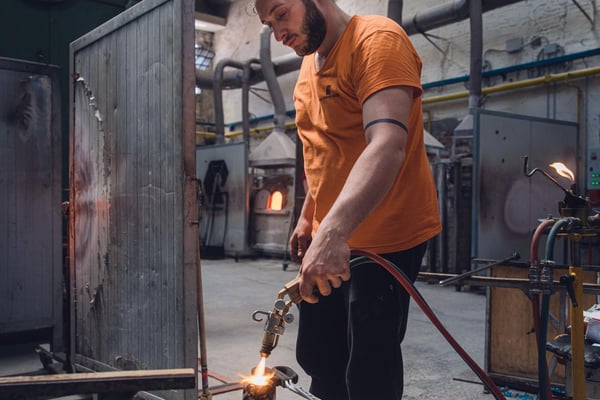 Tourist experiencing the thrill of glassblowing in a Murano workshop, shaping molten glass with a master craftsman. Tourist experiencing the thrill of glassblowing in a Murano workshop, shaping molten glass with a master craftsman.