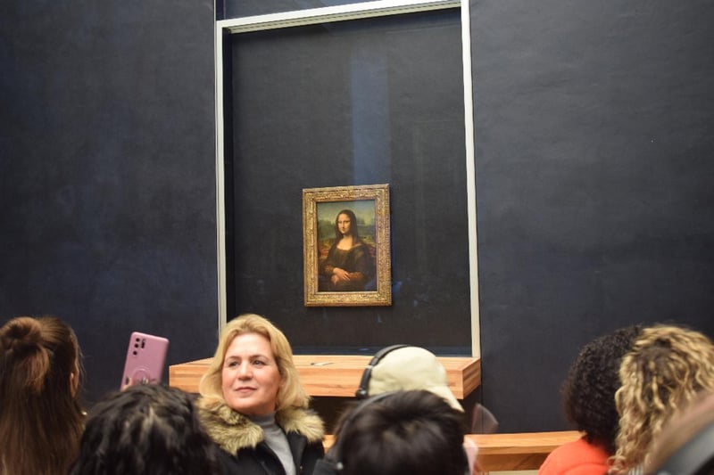 Small guided tour group admiring the Mona Lisa painting inside the Louvre Museum in Paris Small guided tour group admiring the Mona Lisa painting inside the Louvre Museum in Paris