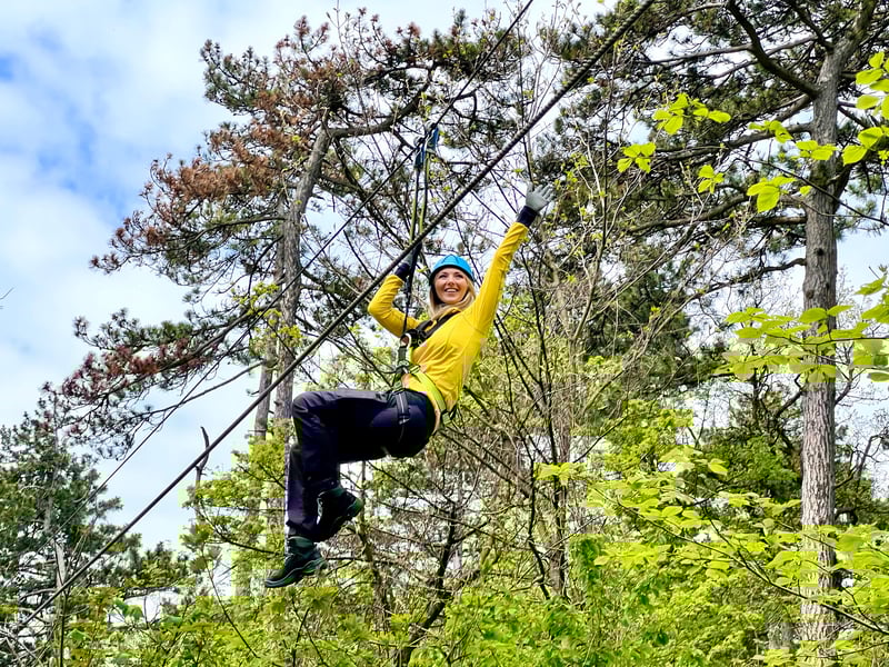Adventurer on a high ropes course in Vienna's Kahlenberg forest with the city skyline visible below Adventurer on a high ropes course in Vienna's Kahlenberg forest with the city skyline visible below