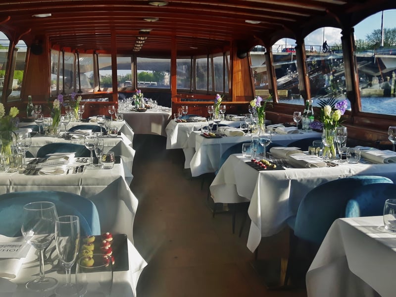 Luxury dinner cruise on Amsterdam canals at night with elegant table setting and illuminated bridges Luxury dinner cruise on Amsterdam canals at night with elegant table setting and illuminated bridges