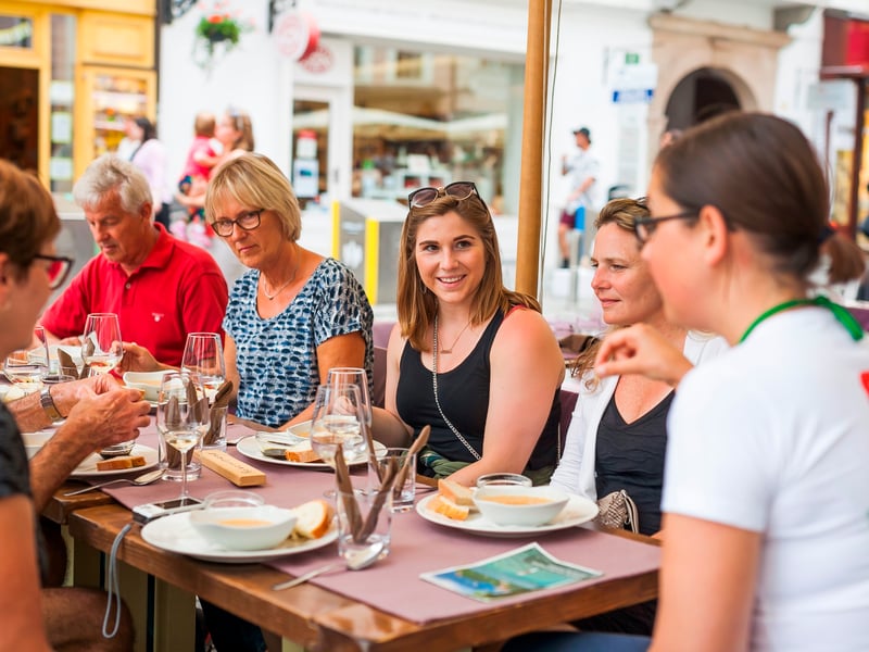 Group enjoying a traditional Slovenian food and wine tasting tour in Ljubljana's old town Group enjoying a traditional Slovenian food and wine tasting tour in Ljubljana's old town
