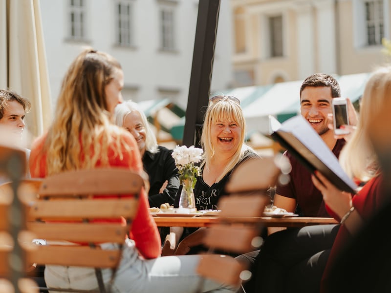 Traditional Slovenian food and wine tasting on a wooden table during a Ljubljana food tour with old town architecture in the background. Traditional Slovenian food and wine tasting on a wooden table during a Ljubljana food tour with old town architecture in the background.