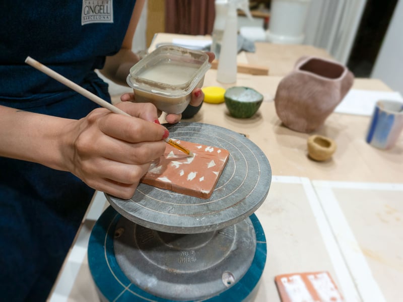 Close-up of hands painting a colorful ceramic tile in a traditional Barcelona artisan workshop Close-up of hands painting a colorful ceramic tile in a traditional Barcelona artisan workshop