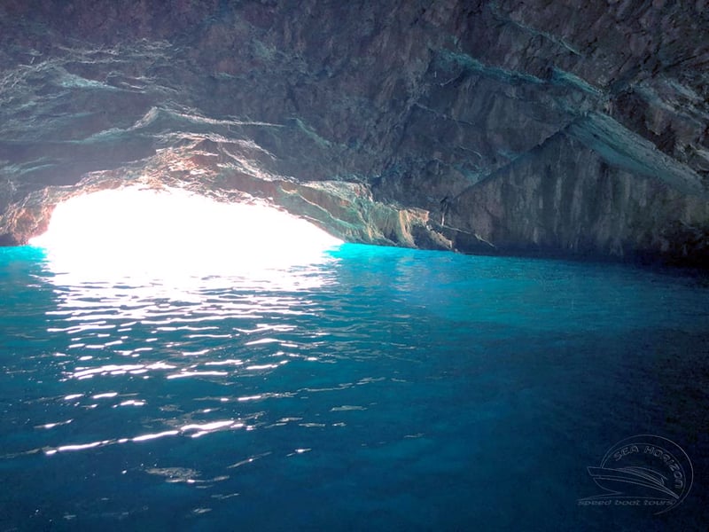 Speedboat entering the glowing Blue Cave in Montenegro with passengers enjoying the turquoise waters Speedboat entering the glowing Blue Cave in Montenegro with passengers enjoying the turquoise waters