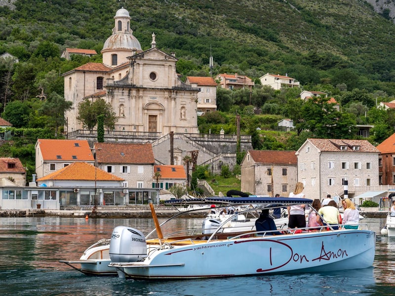 Traditional tour boat cruising the stunning blue waters of Boka Bay Montenegro past the historic Our Lady of the Rocks islet Traditional tour boat cruising the stunning blue waters of Boka Bay Montenegro past the historic Our Lady of the Rocks islet