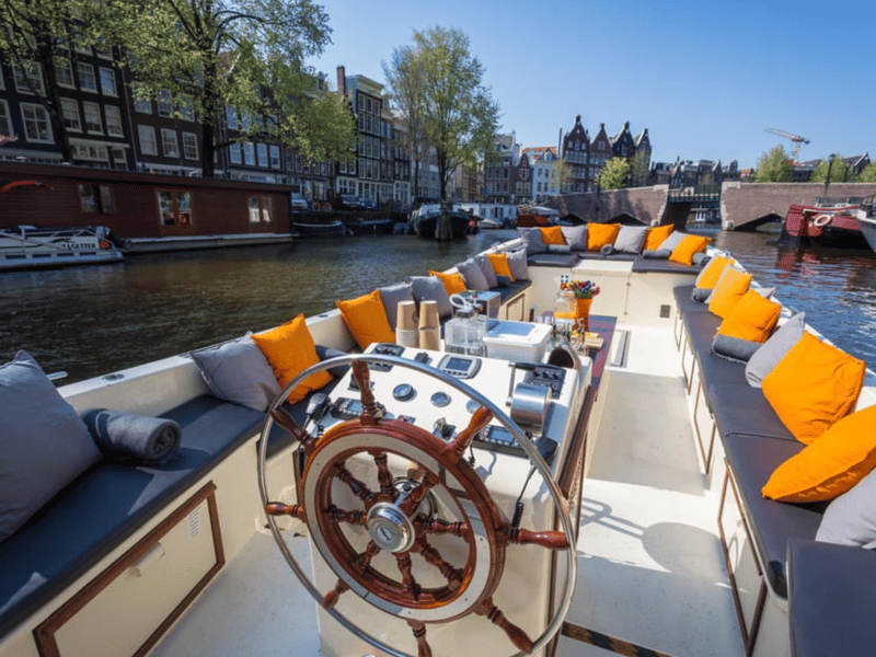 Modern electric canal boat passing under the illuminated Skinny Bridge in Amsterdam at dusk with happy passengers Modern electric canal boat passing under the illuminated Skinny Bridge in Amsterdam at dusk with happy passengers