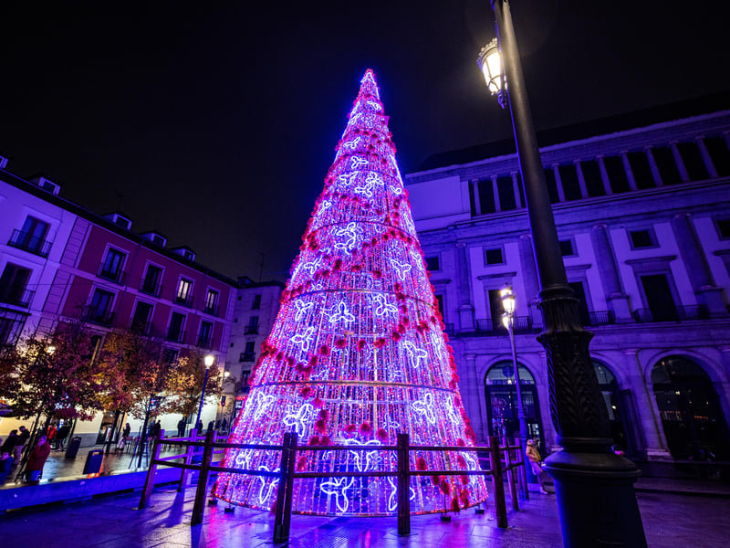 Red open-top hop-on-hop-off sightseeing bus driving past the Royal Palace of Madrid with tourists on board Red open-top hop-on-hop-off sightseeing bus driving past the Royal Palace of Madrid with tourists on board
