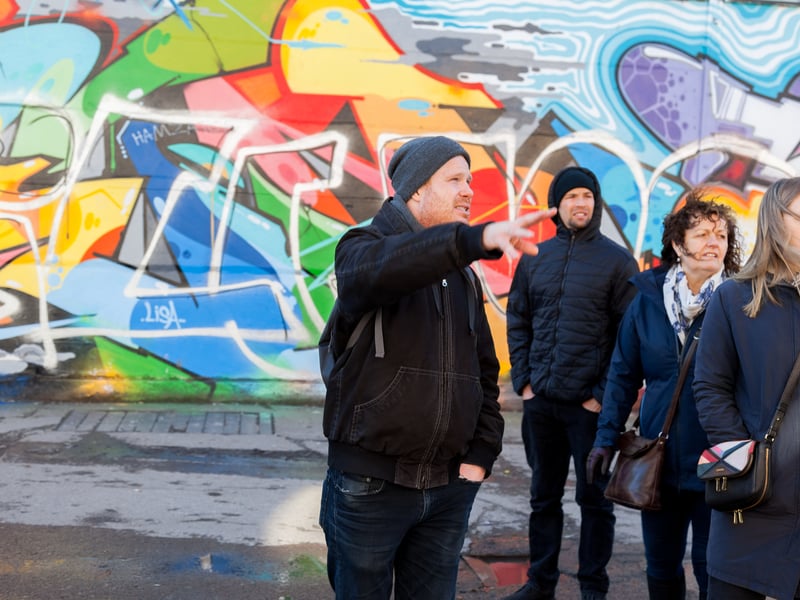 A group enjoying a Berlin hidden gems food tour with local tastings in a sunlit, historic courtyard adorned with street art. A group enjoying a Berlin hidden gems food tour with local tastings in a sunlit, historic courtyard adorned with street art.
