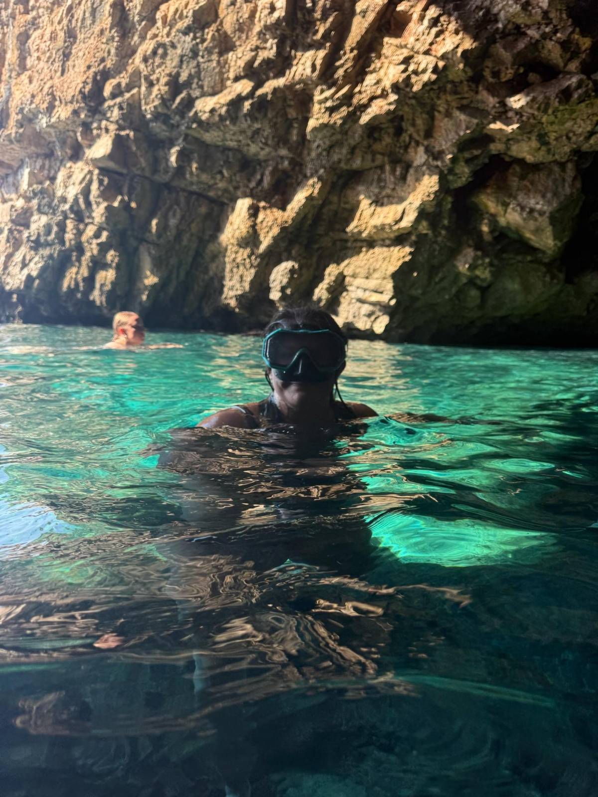 A snorkeler in the turquoise water of a sea cave