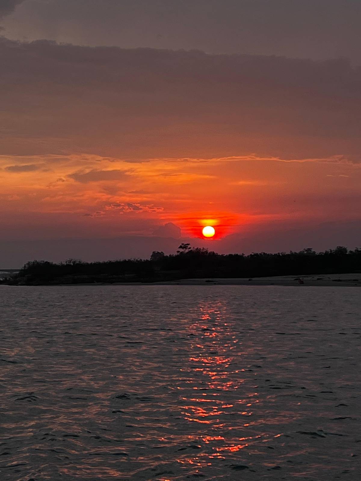 El sol poniéndose rojo sobre un río ancho