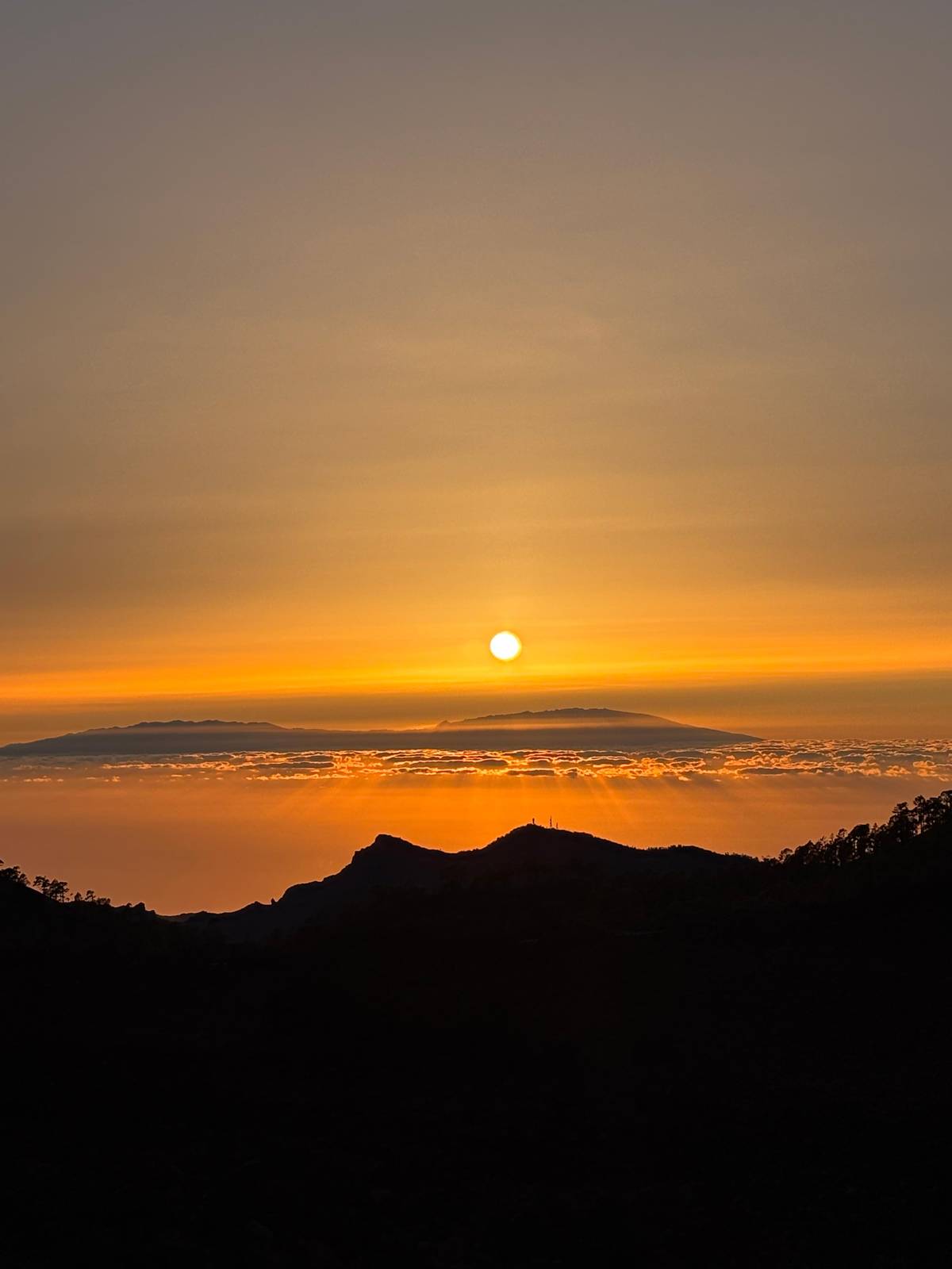 The sun going down over the clouds and a distant island