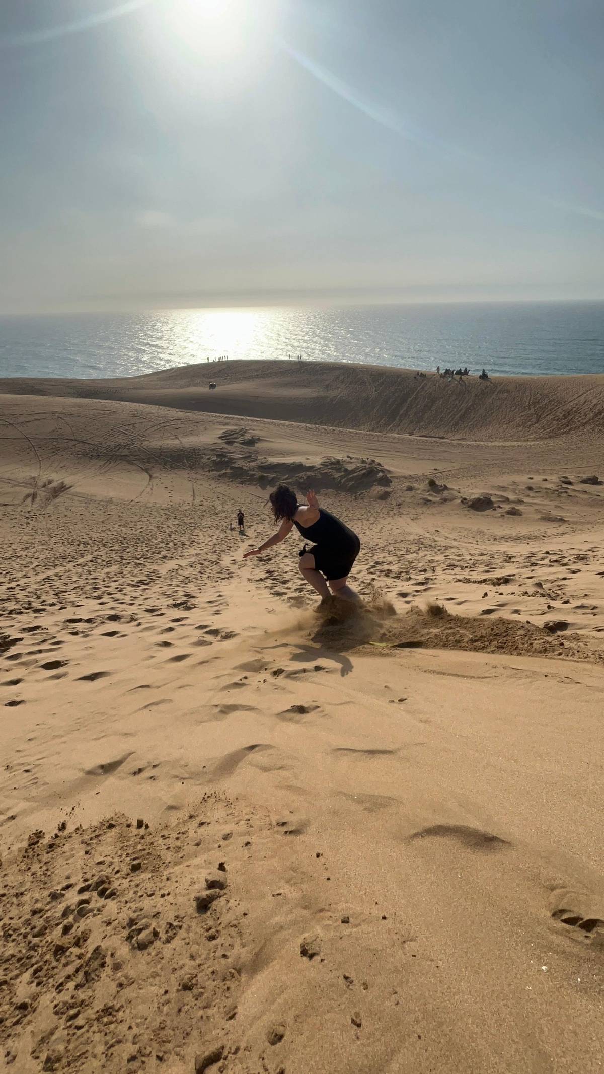 A boarder carving down a dune with the ocean behind