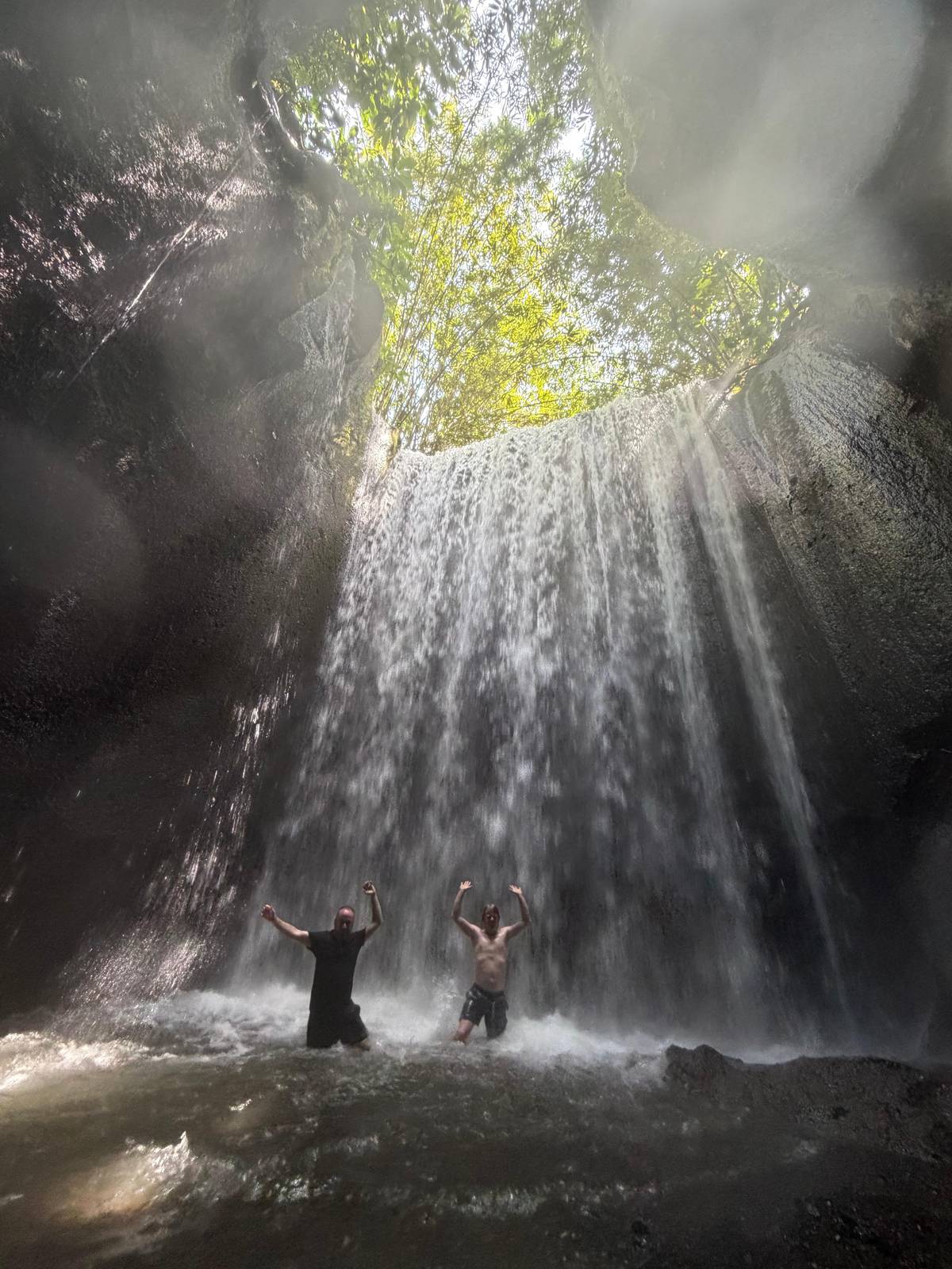 Light falling into a cave where a waterfall pours from above
