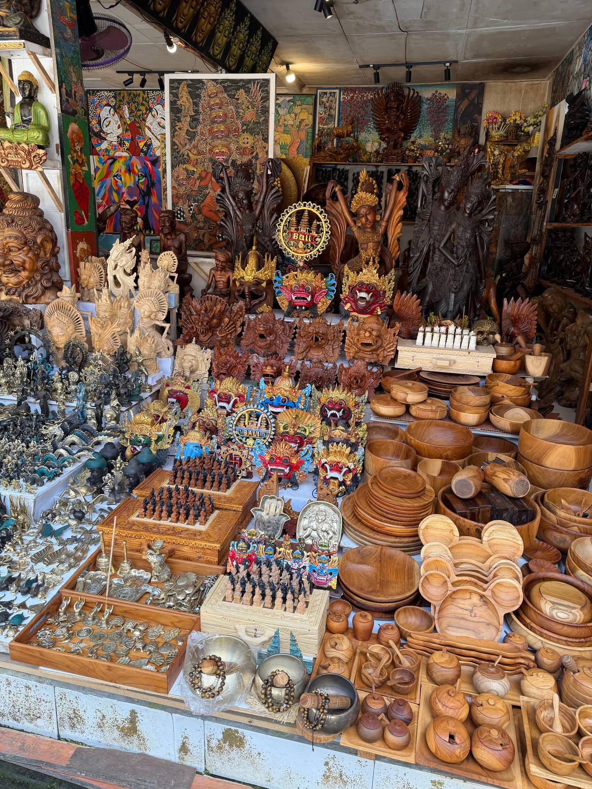 A market stall stacked with wooden bowls and carved masks