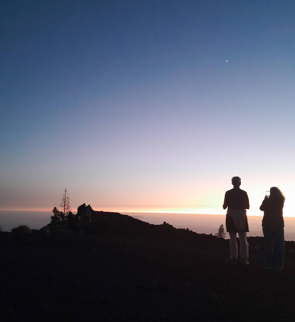 Two people watching the last light from a ridge