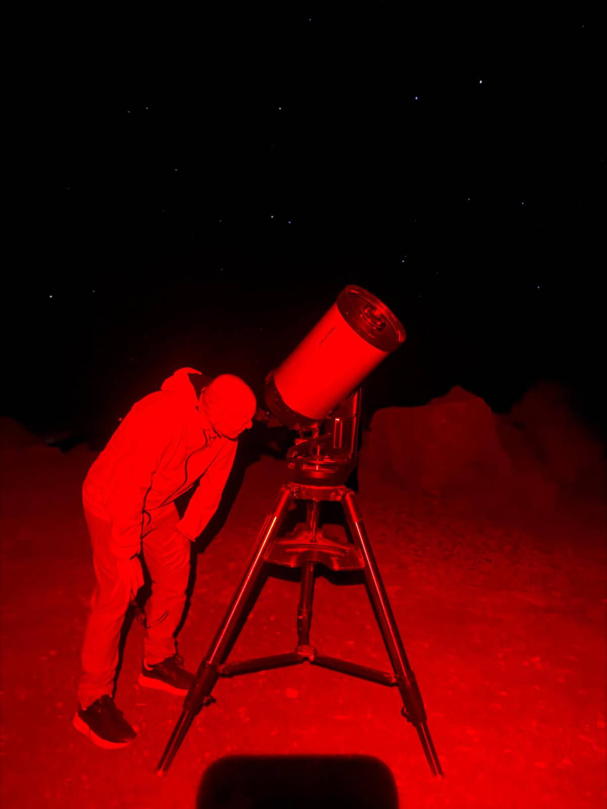 A guide at a telescope lit by red light at night