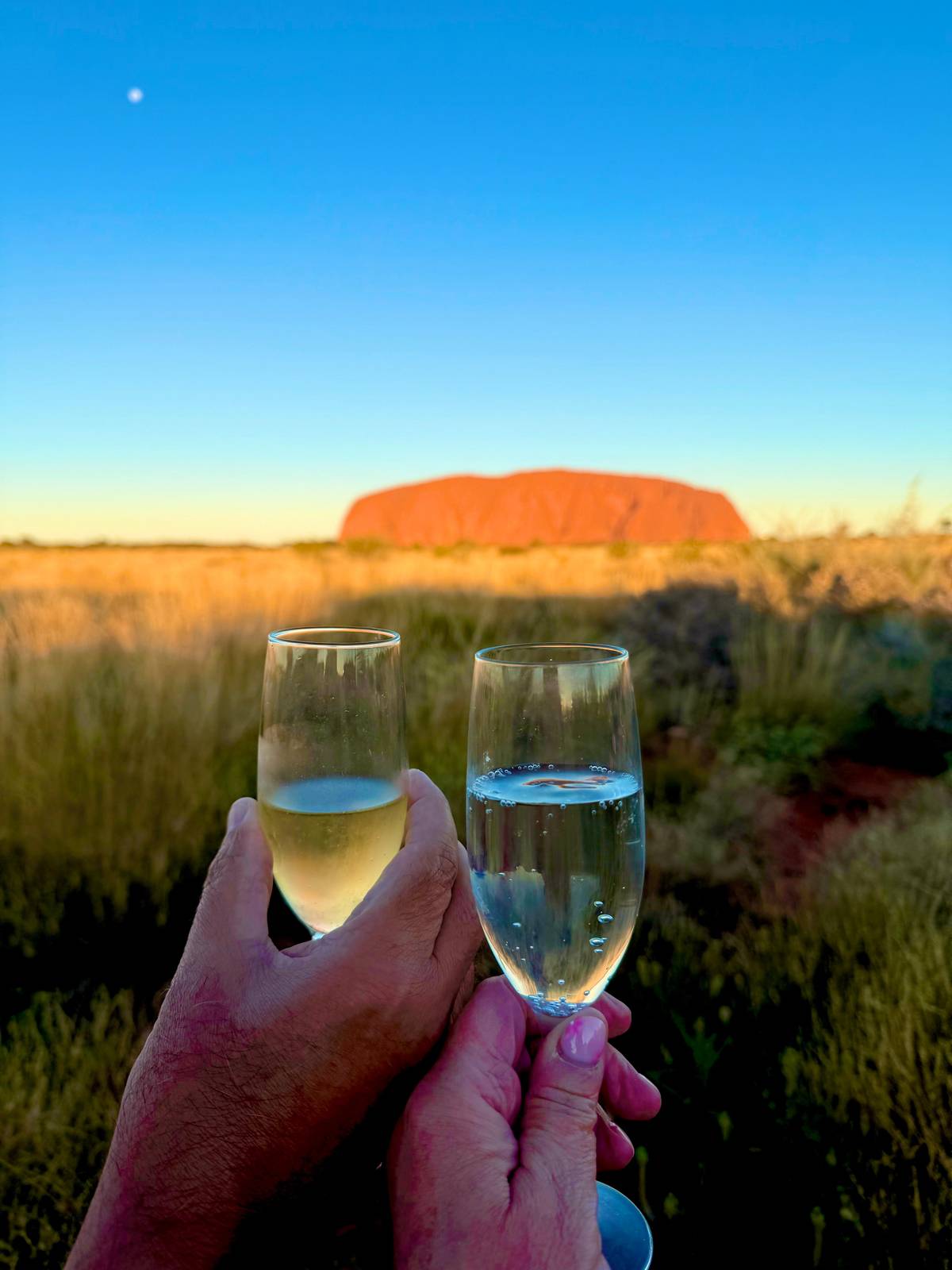 A toast at sunset with the rock behind the glasses