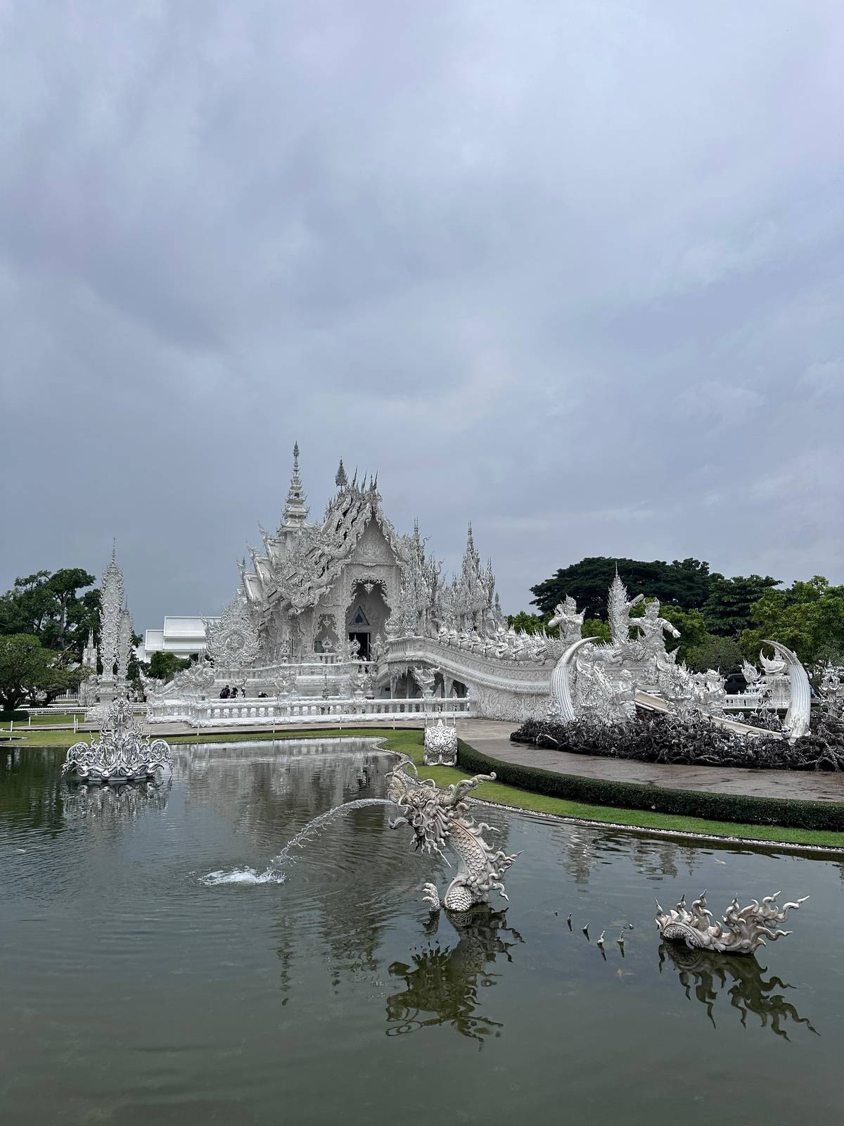 The White Temple reflected in its pond with a fountain