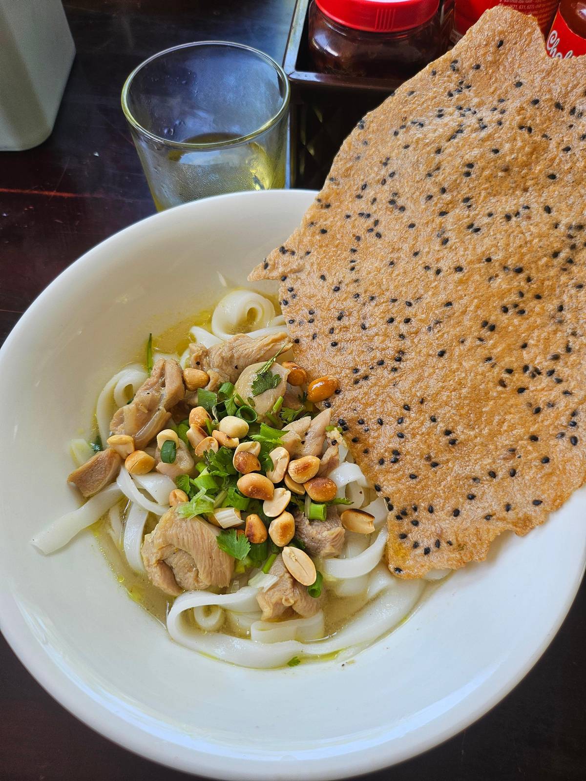 Un bol de fideos Quang con una galleta de arroz de sésamo