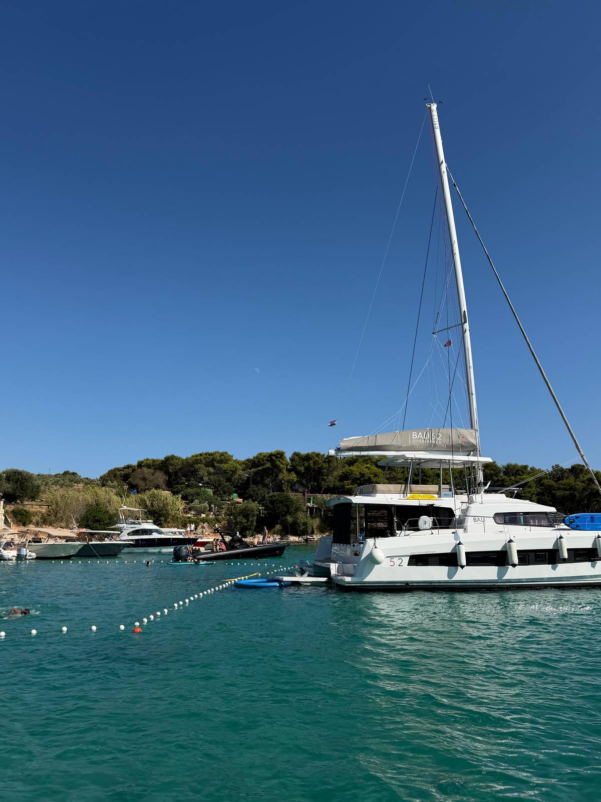 A sailing catamaran in a sheltered bay