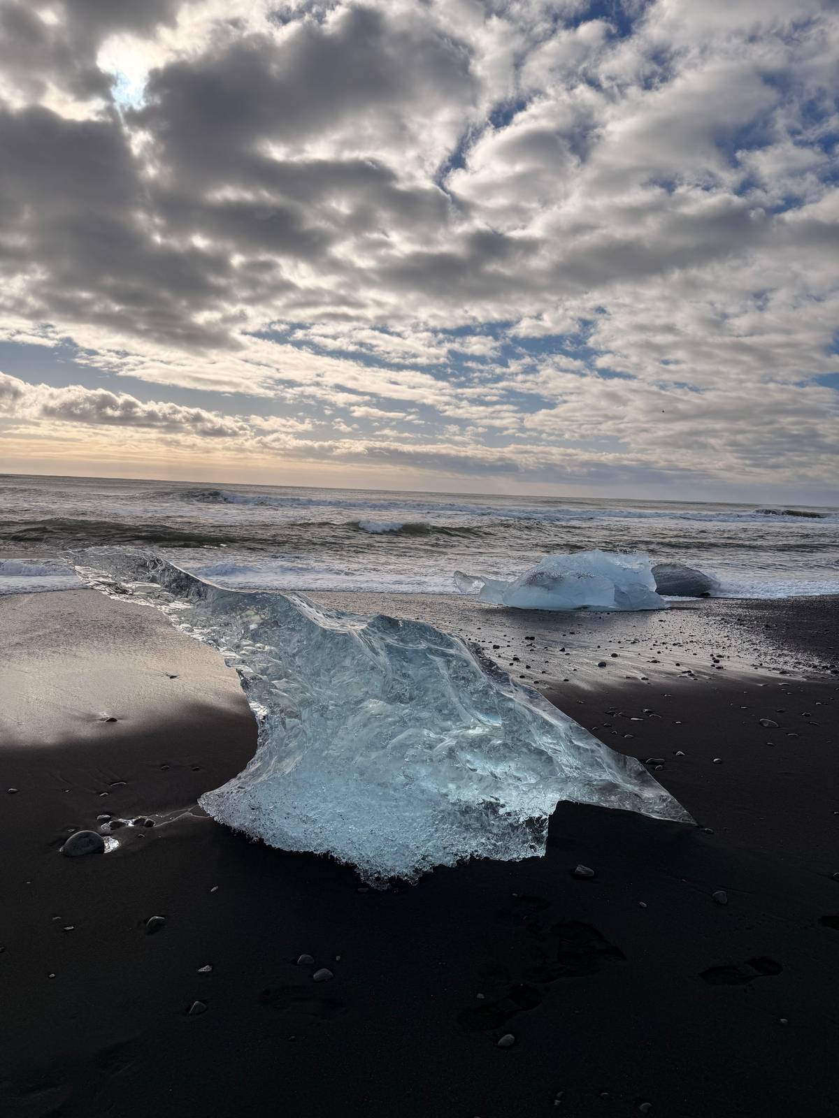 A clear iceberg washed up on black sand