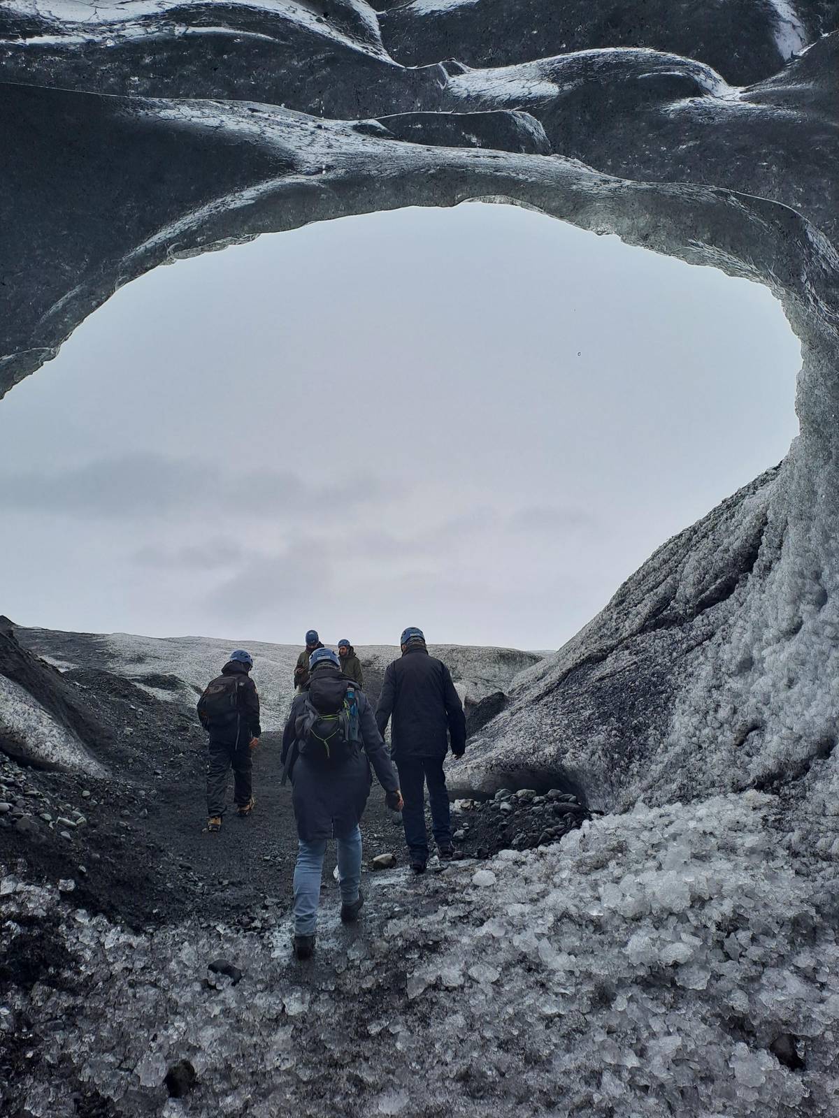 A group walking into a wide ice cave mouth