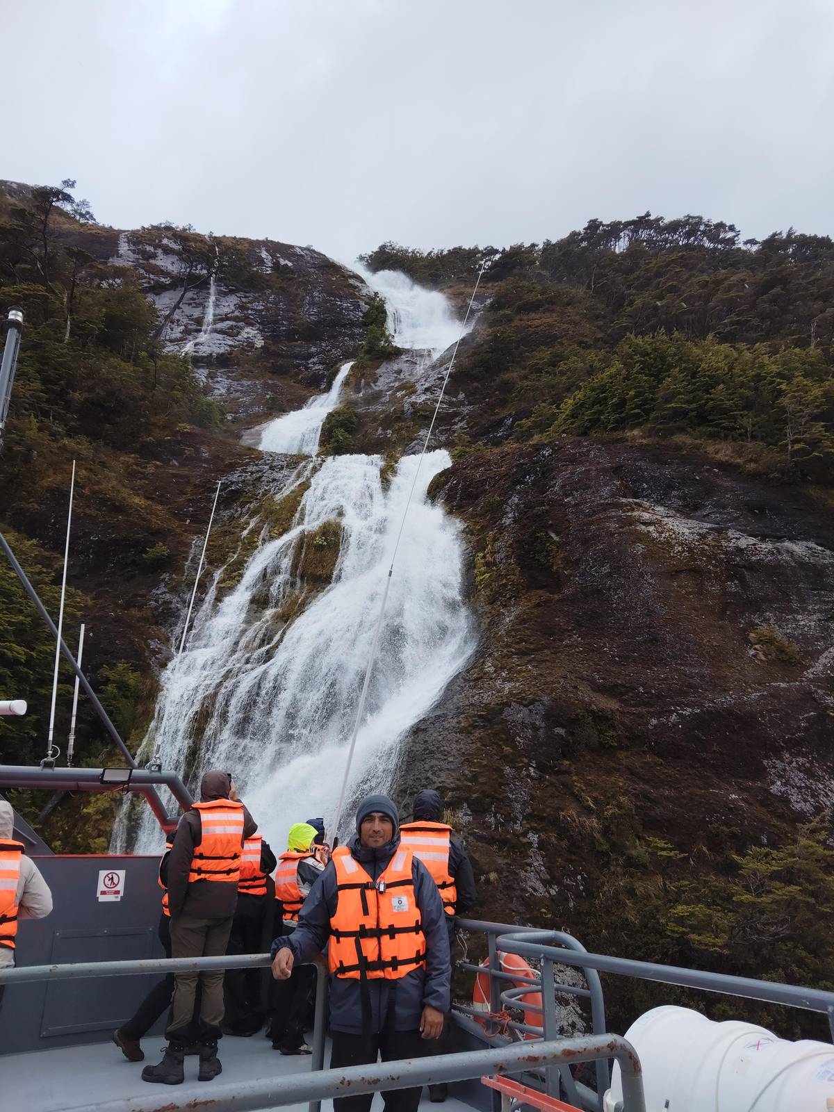 Guests in life jackets on the bow below a waterfall