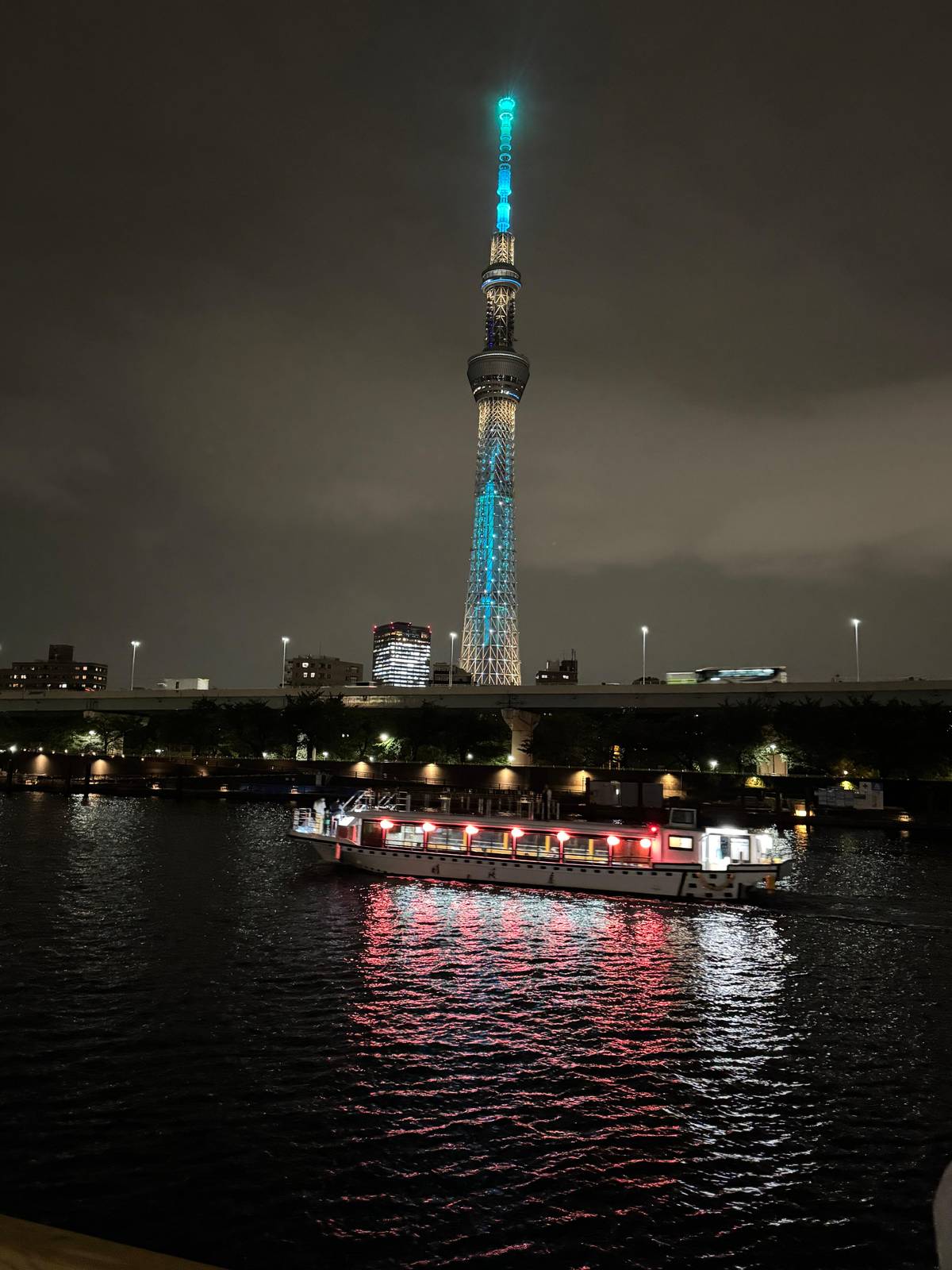 A lit yakatabune on the Sumida River below Tokyo Skytree