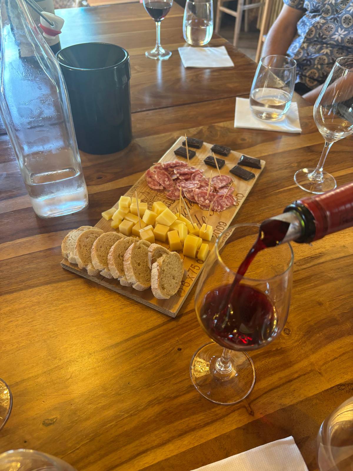 Red wine poured beside a platter of cheese and charcuterie