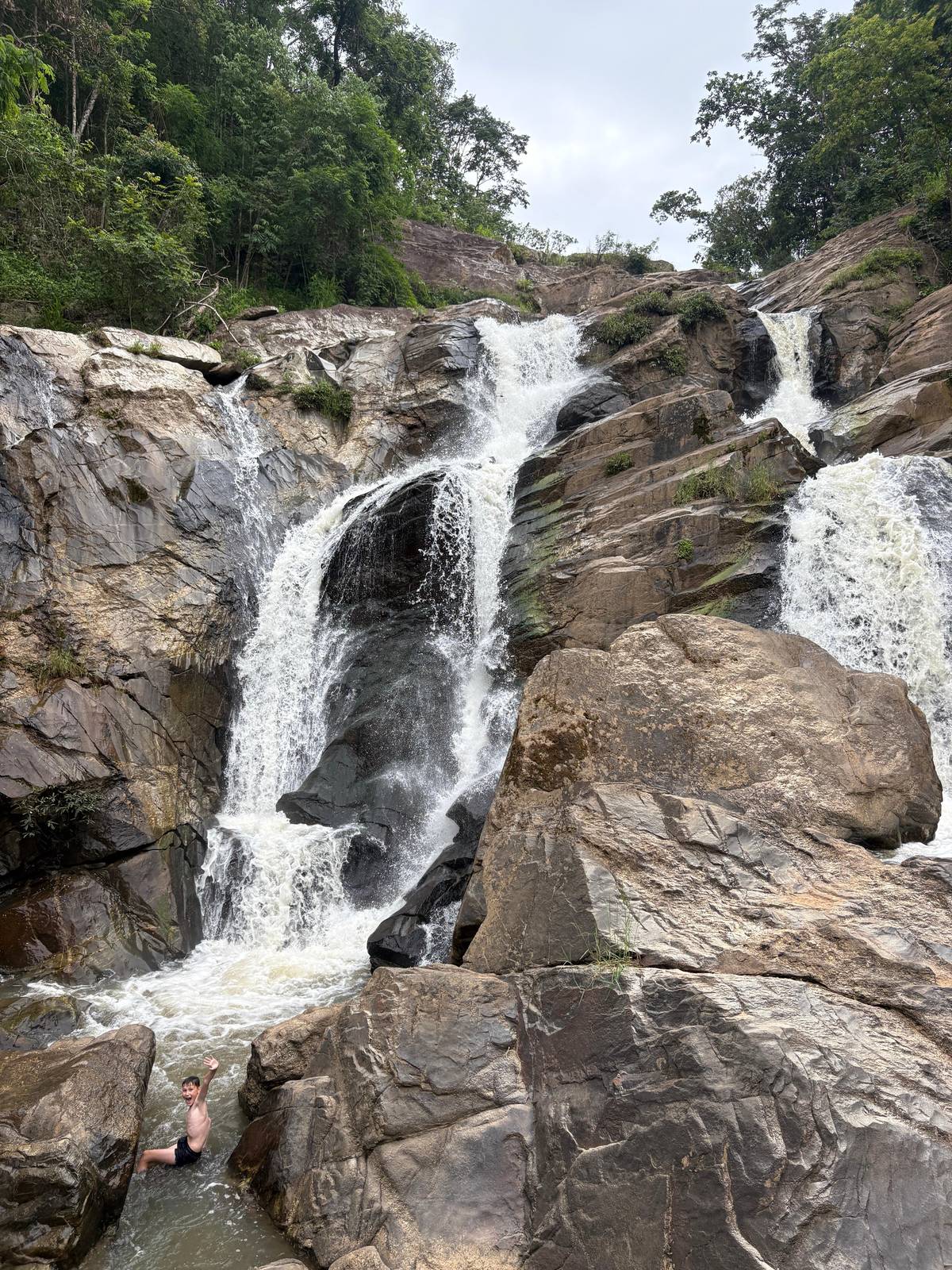 Water spilling over dark boulders at a forest waterfall