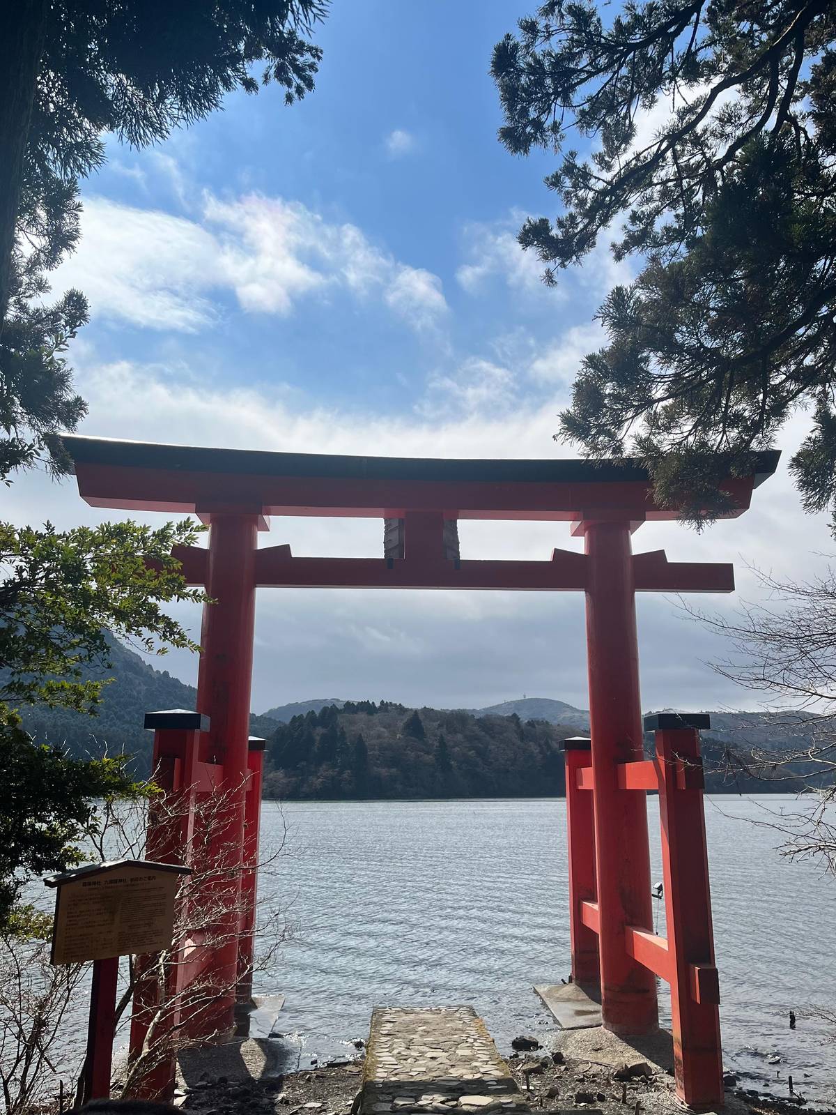 A red torii on the shore looking out over Lake Ashi