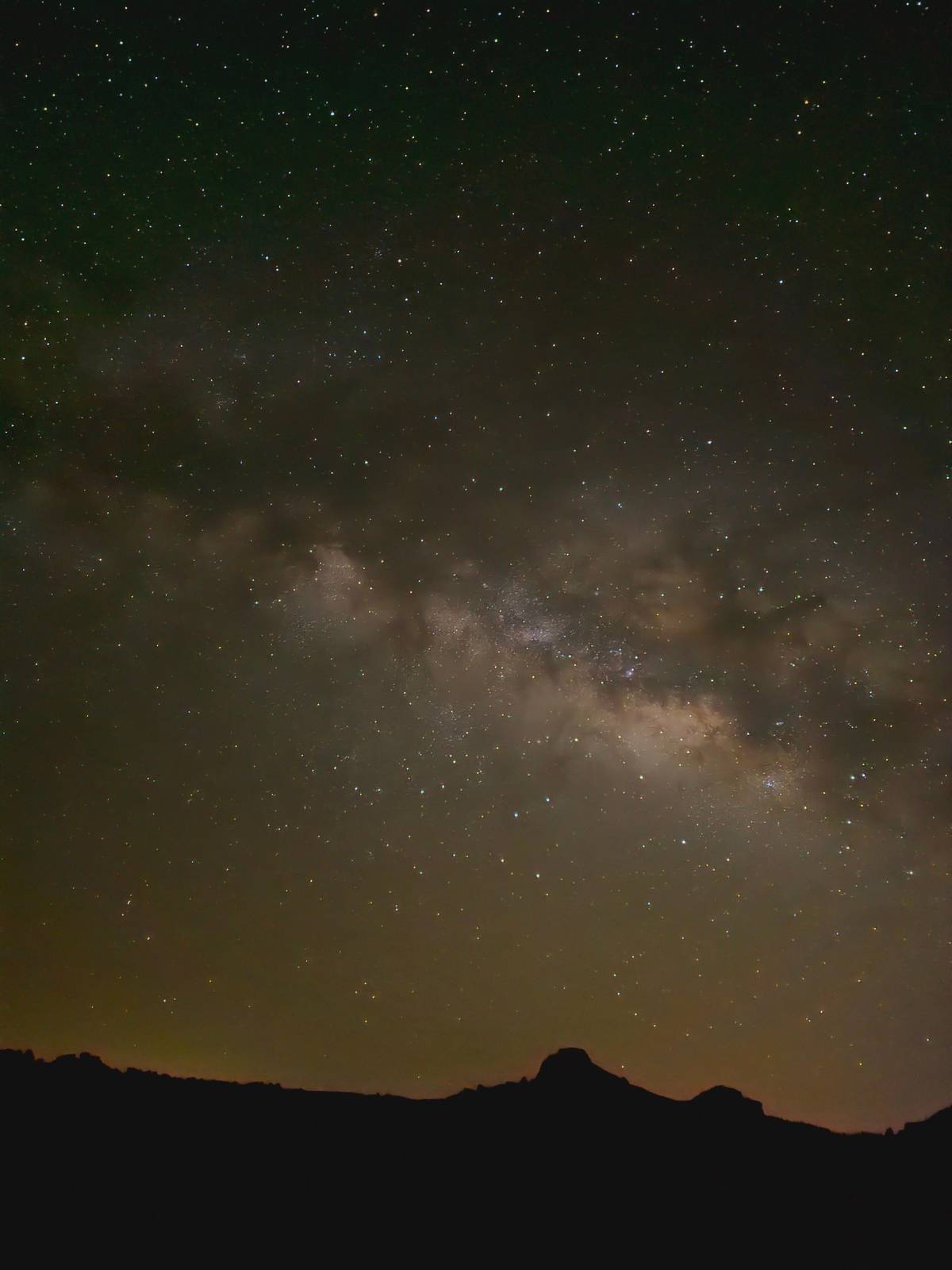 The Milky Way above a dark volcanic skyline