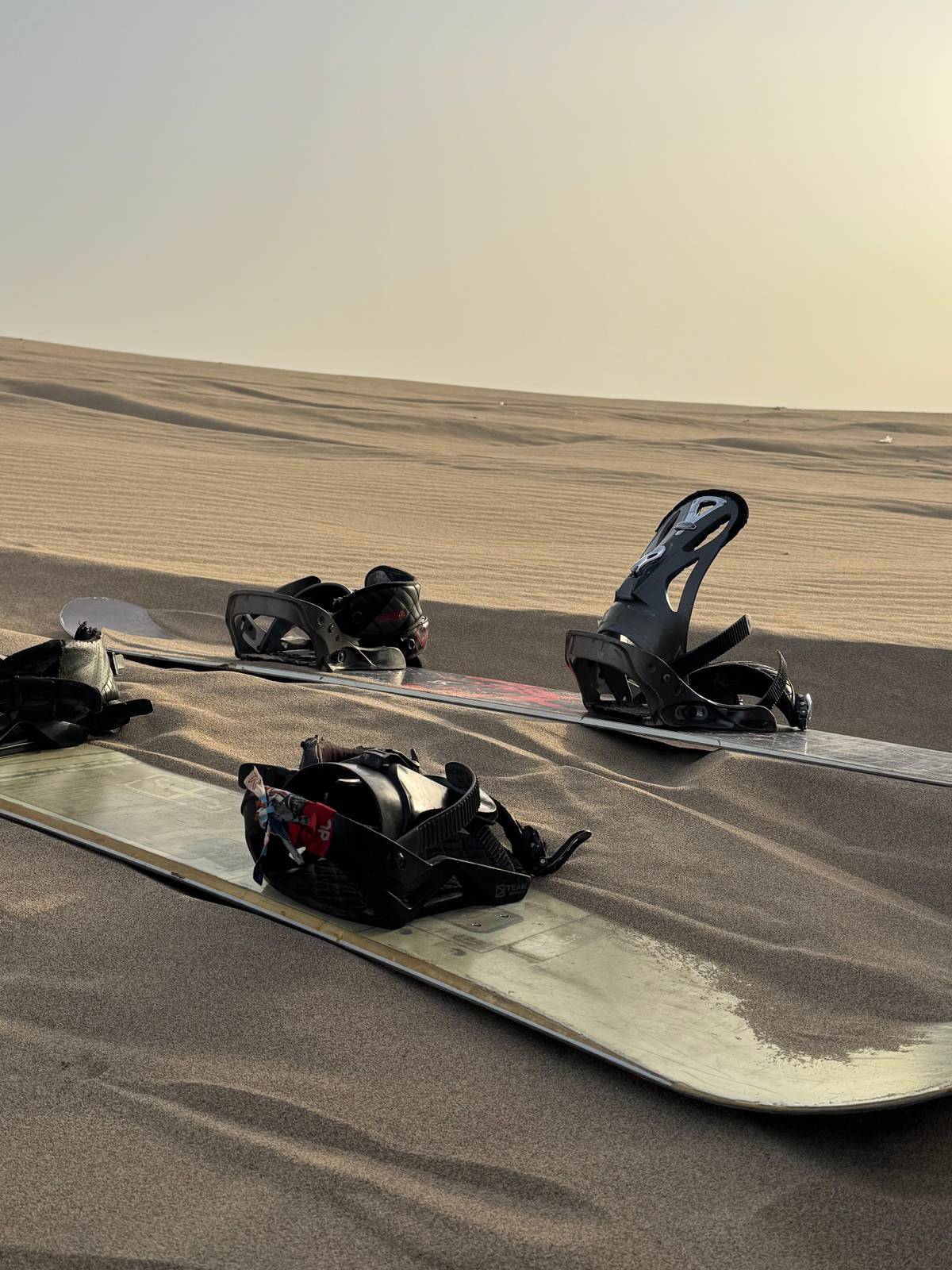 Snowboards with bindings and boots laid out on the sand