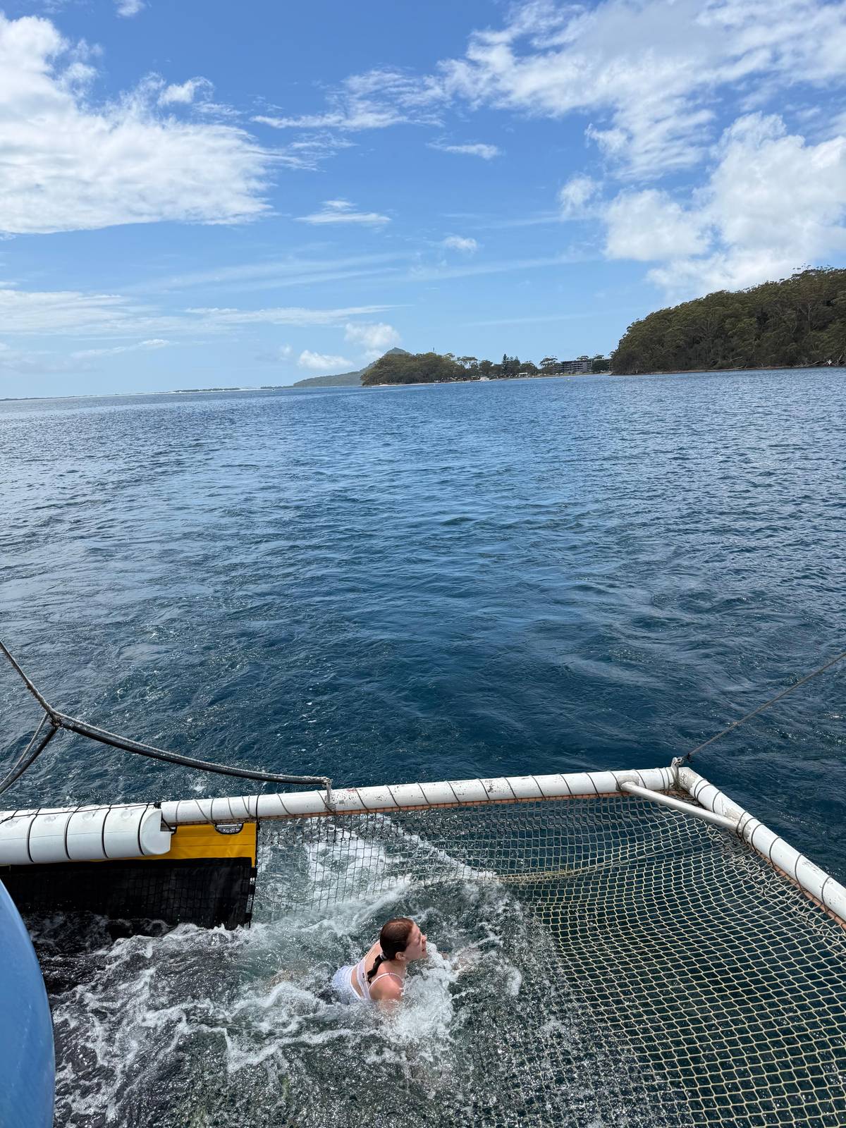 A swimmer splashing in the net behind the boat