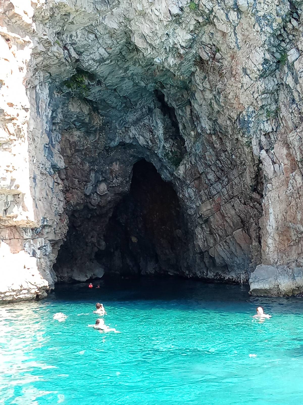 Swimmers at the mouth of a sea cave