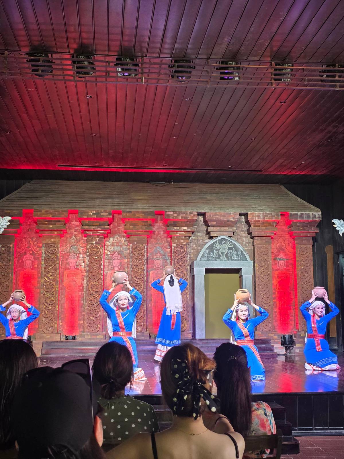 Bailarines con traje champa en un escenario iluminado en rojo