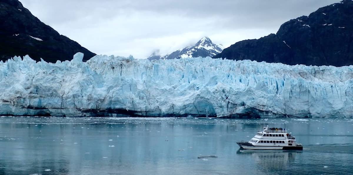 A catamaran in front of a glacier wall