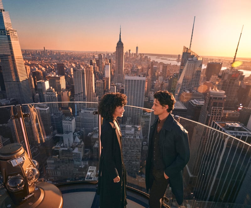 Two visitors at the rail as the sun goes down, the Midtown skyline turning gold