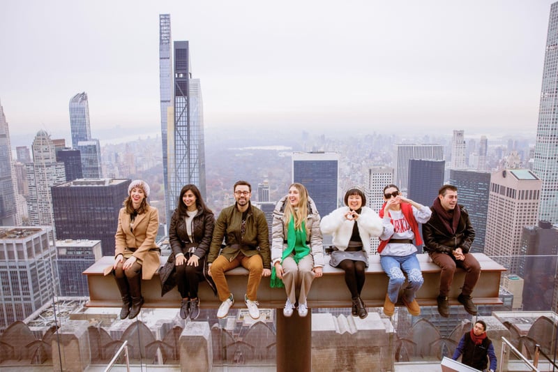 Visitors sitting out on The Beam, the recreated girder from the 1932 lunch-atop-a-skyscraper photograph, Midtown spread out behind them