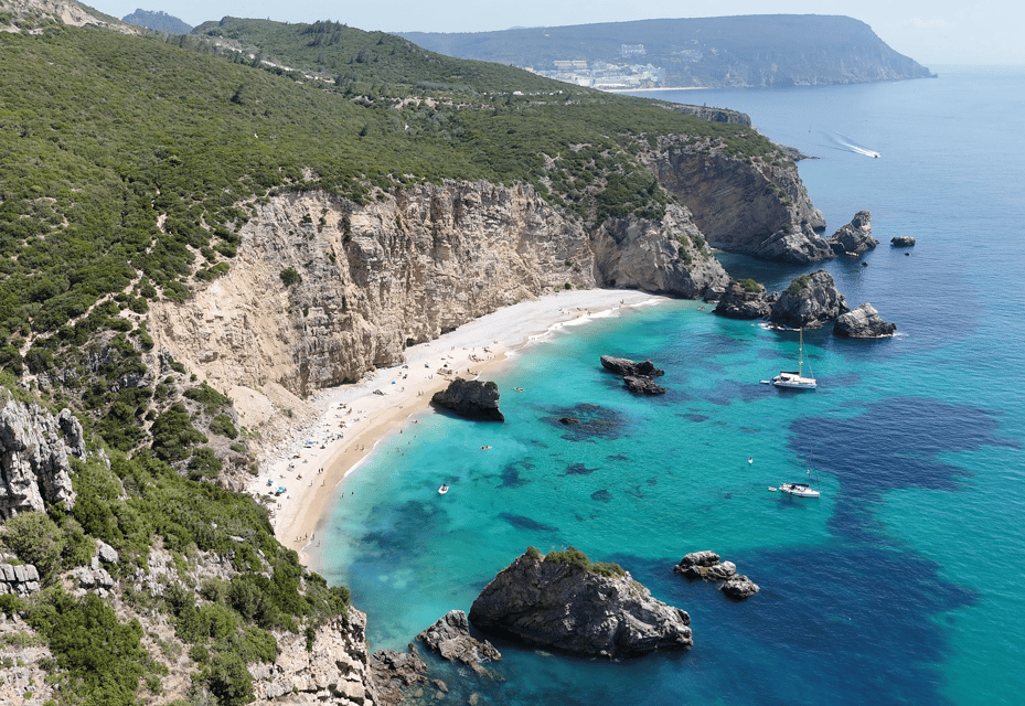 Small pebble cove with turquoise water at the foot of tall cliffs, seen from the sea