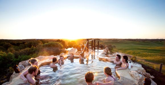 Steam rising from an outdoor thermal pool surrounded by trees