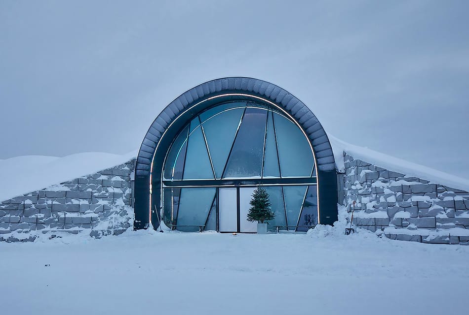 Ice sculptures and a bed covered with reindeer hides inside a blue-lit ice room