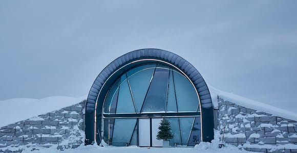 Ice sculptures and a bed covered with reindeer hides inside a blue-lit ice room