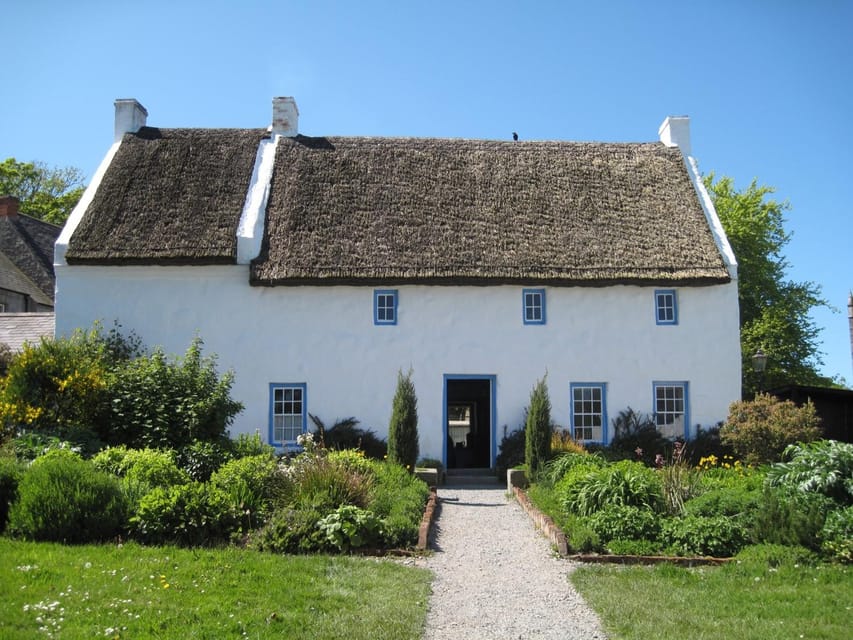 A whitewashed thatched cottage beside a grassy lane