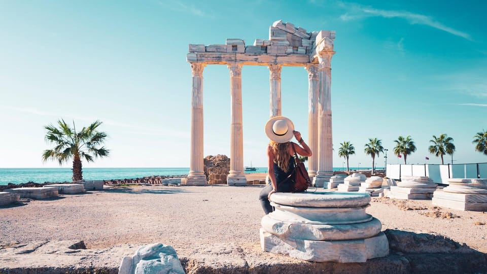 Columns of the Temple of Apollo in Side beside the sea, with a seated visitor in a sun hat in front