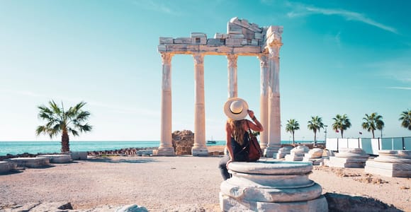 Columns of the Temple of Apollo in Side beside the sea, with a seated visitor in a sun hat in front