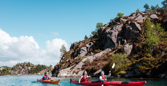 Two sea kayaks moving between low rocky islets off the coast near Bergen
